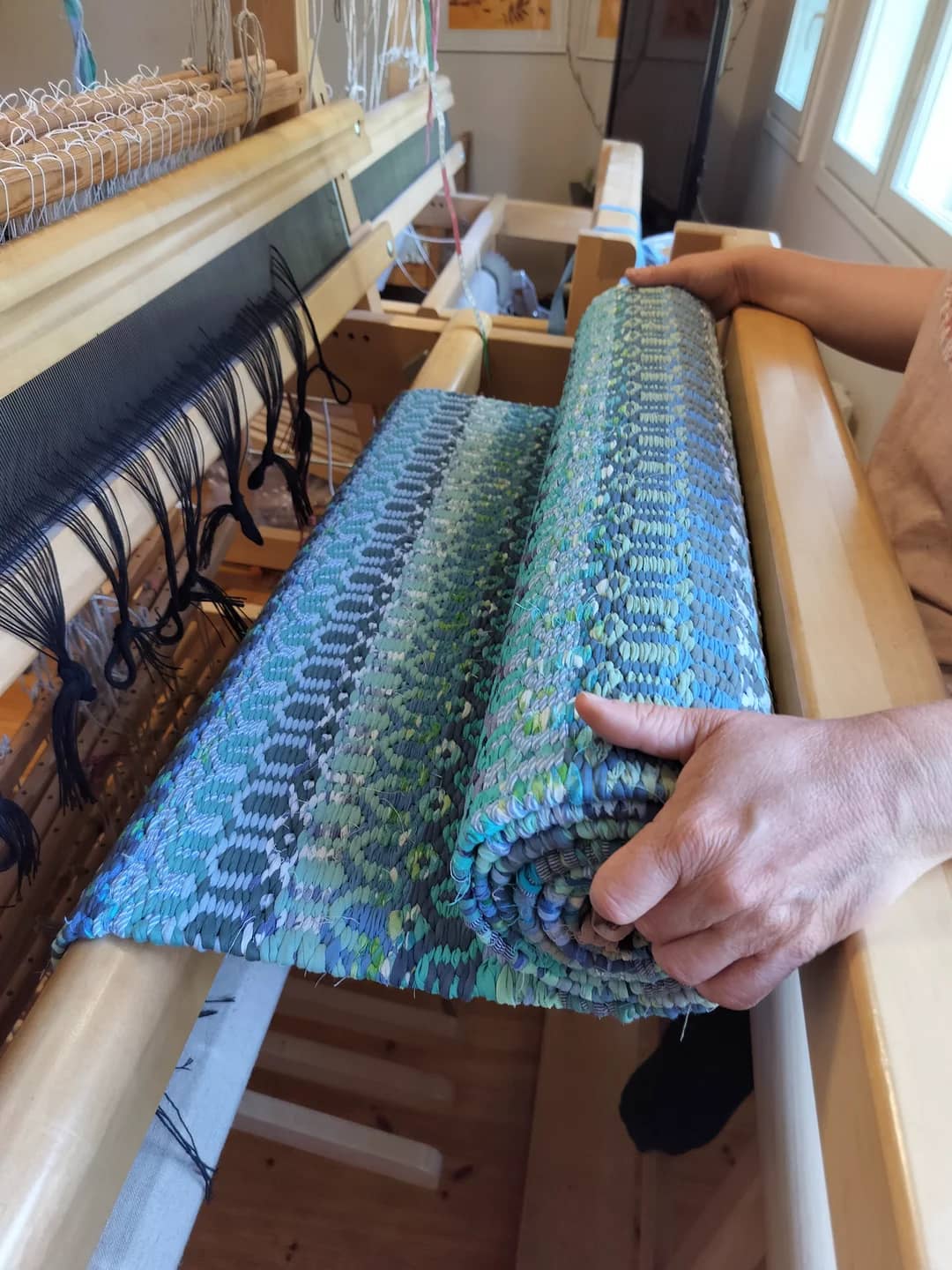 Finished textile artwork unrolled on a light wood floor.