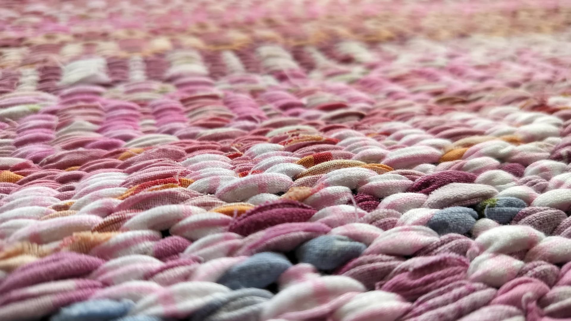 Handwoven textile artwork with warm tones on a light floor.